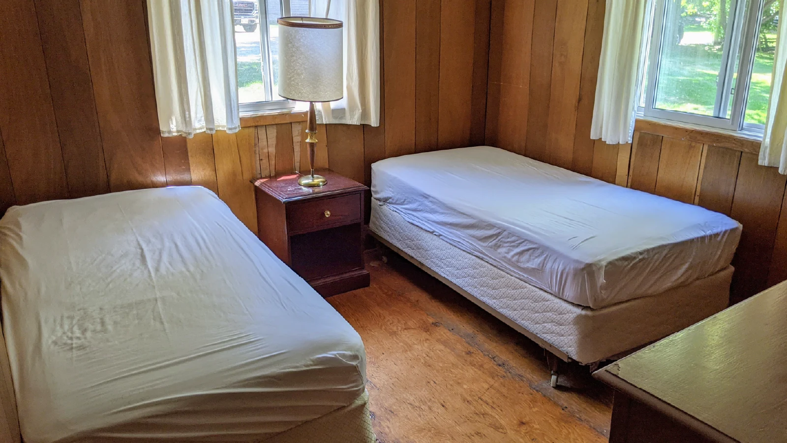 Pigeon Lake Resort Cottage three bedroom with two single beds and nightstand by window.
